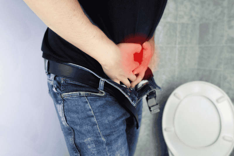 Homem com as mãos na área da próstata sinalizando dor